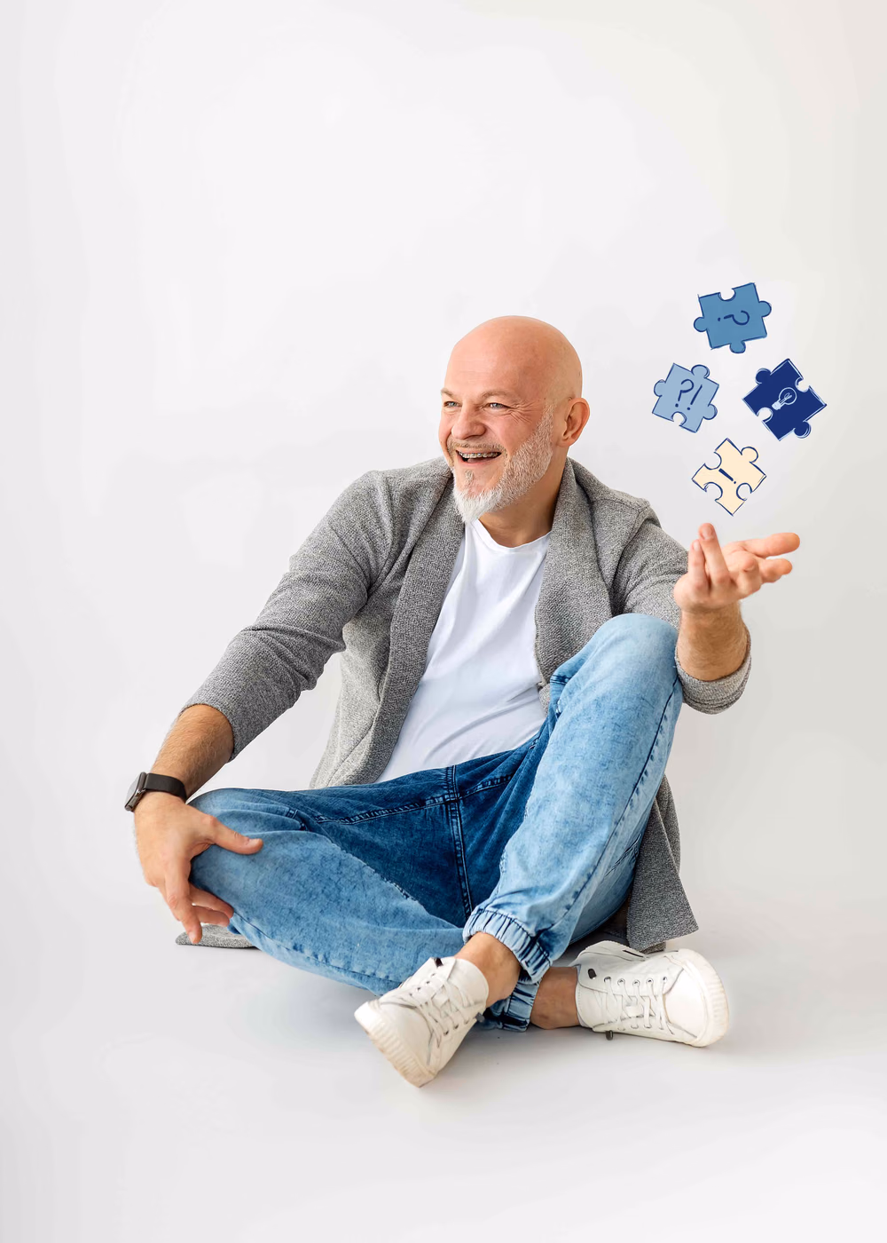 Wojciech Męciński siedzi po turecku i z uśmiechem podrzuca w górę cztery puzzle